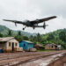 Drone médical à voilure fixe décollant d’une base logistique rurale sur une piste boueuse, avec un paysage verdoyant en Afrique.