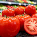 Grappe de tomates rouges dans un supermarché, avec des fruits lisses et une tomate mûre coupée montrant son intérieur juteux.