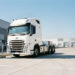 Tracteur routier électrique blanc de 44 tonnes en recharge rapide sur une aire logistique française, avec des bornes haute puissance sous un ciel bleu dégagé.