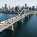 Vue aérienne réaliste du pont international Gordie Howe reliant Windsor et Détroit, avec des camions et des voitures circulant sur le tablier et la rivière Détroit au premier plan.